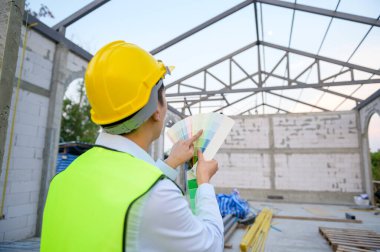 İnşaat alanında renk seçen güvenlik kaskı takan Asyalı bir mühendis. 