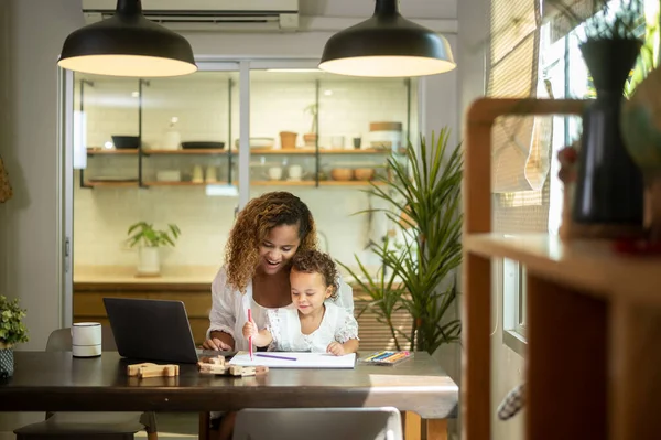 stock image African American mother wearing casual clothes working in her home while daughter playing  or education 