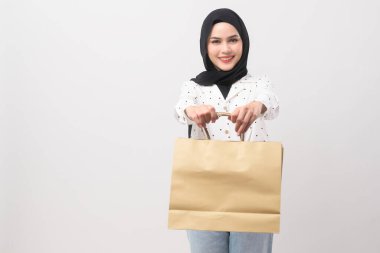 Beyaz arka plan stüdyosu, alışveriş ve finans konsepti üzerinden kredi kartı ve alışveriş çantası tutan güzel Müslüman kadın..