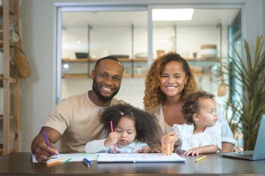 Mutlu Afrika kökenli Amerikalı ebeveynler evde kızlarıyla oynayıp resim çiziyor. 