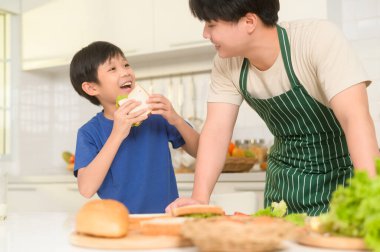 Mutlu Asyalı baba, mutfakta oğluna kahvaltı hazırlıyor.