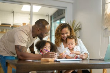 Mutlu Afrika kökenli Amerikalı ebeveynler evde kızlarıyla oynayıp resim çiziyor. 