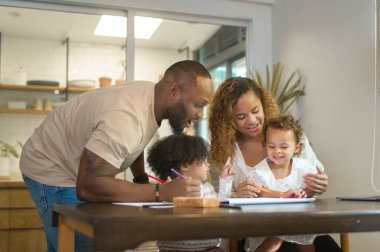 Mutlu Afrika kökenli Amerikalı ebeveynler evde kızlarıyla oynayıp resim çiziyor. 