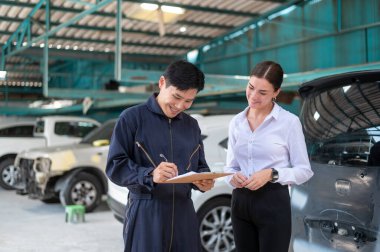 Kafkasyalı genç bir kadın araba tamirhanesindeki tamirciye araba sorunlarını anlatıyor.
