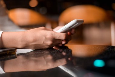 Kafe arka planındaki akıllı telefonu kullanarak kadın elini kapat. 