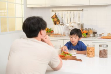 Mutlu Asyalı baba ve oğul evde sağlıklı yiyecekler yiyorlar. 