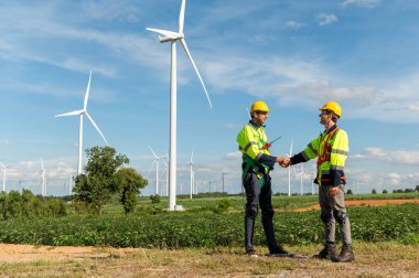  Elektrikli türbinler alanında kaskları olan akıllı mühendisler el sıkışıyor.