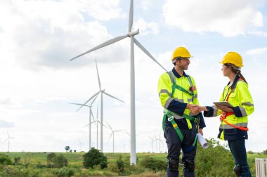 Elektrikli türbinler alanında kaskları olan akıllı mühendisler el sıkışıyor.