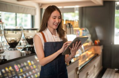 Modern kahve dükkanında hisse senedi veya satış gelirlerini kontrol eden Asyalı bir girişimci, küçük işletme kavramı 