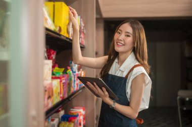 Modern kahve dükkanında hisse senedi veya satış gelirlerini kontrol eden Asyalı bir girişimci, küçük işletme kavramı 