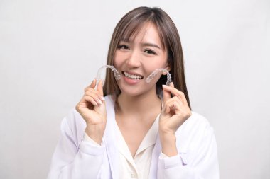 Beyaz arka plan stüdyosu, diş sağlığı hizmetleri ve ortodontik konsept üzerinde diş teli tutan genç bir dişçi.