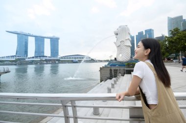 SINGAPORE - 28 / 12 / 2022: Marina Körfezi Sands Oteli önünde genç Asyalı kadın turistle birlikte Merlion Fountain. 