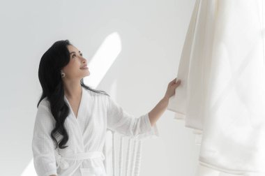 Beyaz banyolu gelin düğün gününe hazırlanan zarif gelinliğe dokunuyor ve hayran kalıyor. Aşk ve evlilik kavramı.