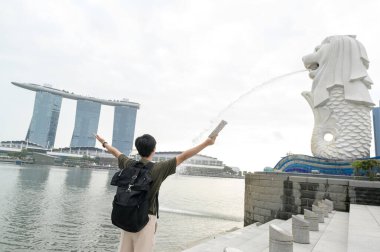 SINGAPORE - 28 / 12 / 2022: Marina Körfezi Sands Oteli önünde genç Asyalı turistle birlikte Merlion Fountain. 