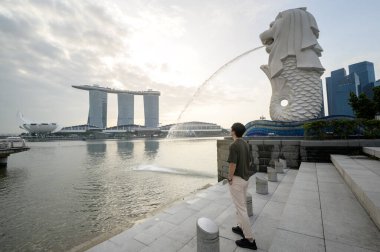 SINGAPORE - 28 / 12 / 2022: Marina Körfezi Sands Oteli önünde genç Asyalı turistle birlikte Merlion Fountain. 