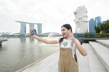 SINGAPORE - 28 / 12 / 2022: Marina Körfezi Sands Oteli önünde genç Asyalı kadın turistle birlikte Merlion Fountain. 