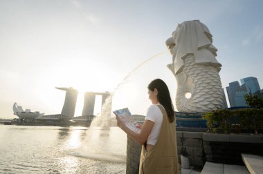 SINGAPORE - 28 / 12 / 2022: Marina Körfezi Sands Oteli önünde genç Asyalı kadın turistle birlikte Merlion Fountain. 