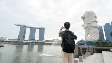 SINGAPORE - 28 / 12 / 2022: Marina Körfezi Sands Oteli önünde genç Asyalı turistle birlikte Merlion Fountain. 