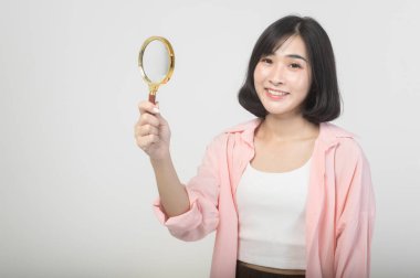 Beyaz arka plan üzerinde büyüteç tutan genç Asyalı kadın, analiz ve finans kavramı