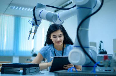 Robot El Programlama ve Yönlendirme, Endüstriyel Robot Tasarımı, Yüksek Teknoloji Tesisi, Modern Makine Öğrenme ile çalışan kadın robotik mühendisi. Seri Üretim Otomatik.