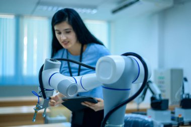 Robot El Programlama ve Yönlendirme, Endüstriyel Robot Tasarımı, Yüksek Teknoloji Tesisi, Modern Makine Öğrenme ile çalışan kadın robotik mühendisi. Seri Üretim Otomatik.