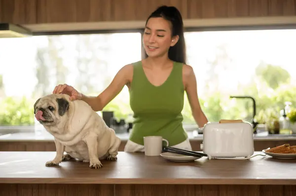 Asian woman preparing coffee and toast bread for breakfast enjoy with dog at the kitchen table in the morning