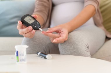 Hamile kadın kan şekerini dijital glikoz ölçer, sağlık bakımı, ilaç, diyabet, glisemi konsepti kullanarak kontrol ediyor.