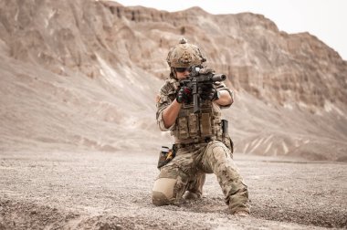 Kamuflaj üniformalı askerler tüfeklerini doğrultuyorlar.