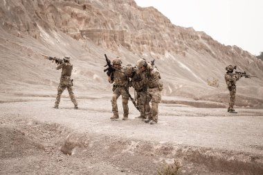 Kamuflaj üniformalı askerler tüfeklerini doğrultuyorlar.