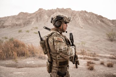 Kamuflaj üniformalı askerler tüfeklerini doğrultuyorlar.