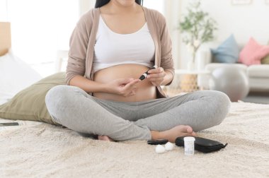Pregnant woman checking blood sugar level by using Digital Glucose meter, health care, medicine, diabetes, glycemia concept clipart