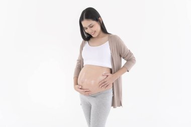 Güzel hamile bir kadın nemlendirici sürüyor, göbeğinde gerilme izi kremi, kısırlık tedavisi, tüp bebek, gelecekteki annelik konsepti.