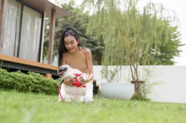 Mutlu Asyalı kadın arka bahçede sevimli akıllı köpek yavrusuyla oynuyor.