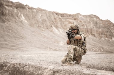 Kamuflaj üniformalı askerler tüfeklerini doğrultuyorlar.