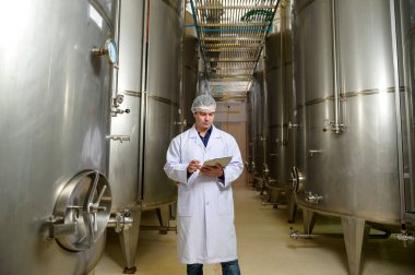 Şarap üretim sürecini ve şarap fabrikasının kalitesini kontrol eden profesyonel şarap üreticisi.