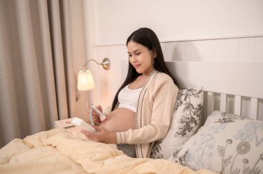 Bebeğin karnındaki kalp atışlarını, kısırlık tedavisini, tüp bebek konseptini dinlemek için cep bebeği doppler 'ı tutan hamile güzel bir kadın.