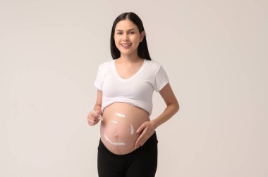 Güzel hamile bir kadın nemlendirici sürüyor, göbeğinde gerilme izi kremi, kısırlık tedavisi, tüp bebek, gelecekteki annelik konsepti.