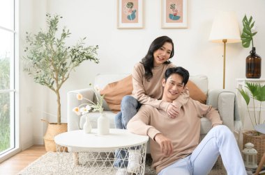 Evdeki oturma odasında oturan Asyalı genç çiftin portresi.