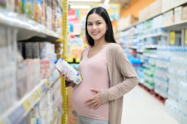 Güzel hamile kadın marketten süt alıyor.