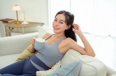 Genç Asyalı kadın evde kahve içmekten zevk alıyor.