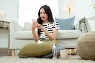 Genç Asyalı kadın oturma odasında kendini hasta hissediyor.