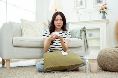 Genç Asyalı kadın oturma odasında kendini hasta hissediyor.