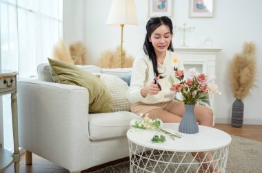 Asyalı gülümseyen kadın kavanoza güzel çiçekler koyuyor