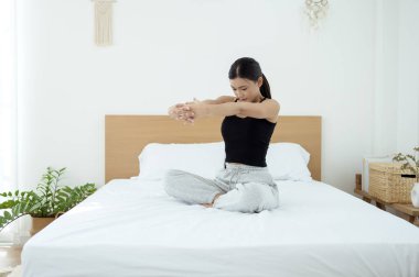 Genç Asyalı kadın yatak odasında egzersiz yapıyor.