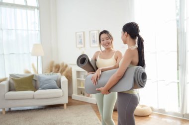 Evde yoga yaptıktan sonra rahatlayan iki genç Asyalı kadın arkadaş..