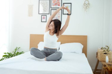 Genç Asyalı kadın yatak odasında egzersiz yapıyor.