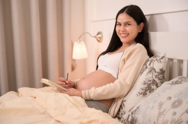 Güzel hamile bir kadın bebeğe günlük yazıyor, kısırlık tedavisi, tüp bebek, gelecekteki annelik konsepti.