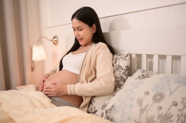 Güzel hamile bir kadın bebeğin gelişimini, doğurganlık tedavisini, tüp bebek konseptini, doğurganlık tedavisini, tüp bebek tedavisini, gelecekteki annelik konseptini teşvik etmek için karnında bebekle konuşuyor. 