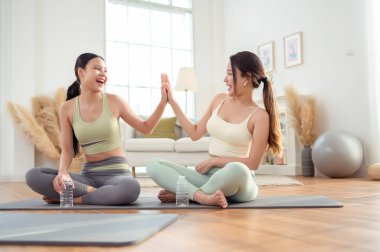 Evde yoga yaptıktan sonra rahatlayan iki genç Asyalı kadın arkadaş..