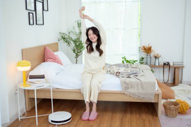 Genç Asyalı kadın sabah uyandıktan sonra yatakta geriniyor.